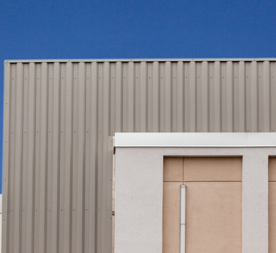 Vertical oriented metal trim cladding creates a façade on building entryway.
